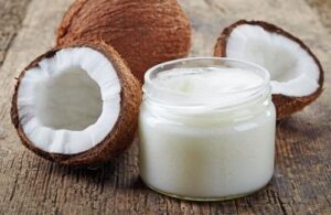 Barattolo di olio di cocco su una panca con tre cocchi