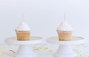 photograph-of-two-identical-cupcakes-with-white-icing-and-a-toothpick-sticking-out-side-by-side-on-identical-white-stands-m.jpg