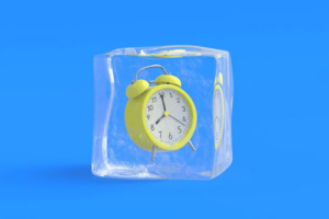 yellow-alarm-clock-suspended-in-a-cube-of-ice-on-a-blue-background-m.png