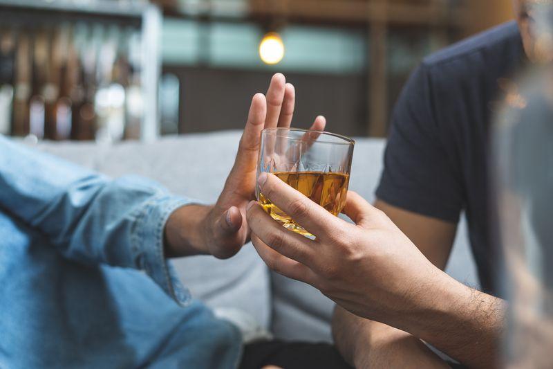 person-in-blue-shirt-right-pushing-away-a-glass-of-brown-liquor-that-someone-else-is-handing-to-them-m-1.jpg