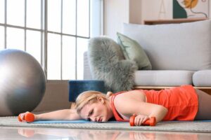 person-in-orange-tank-top-holding-orange-dumbbells-lying-on-floor-looking-tired-and-distressed-m.jpg