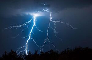 due fulmini massicci che colpiscono una foresta buia contro un cielo blu scuro