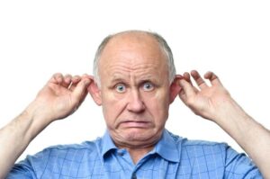 photograph-of-an-older-man-in-a-blue-shirt-pulling-out-his-ears-and-making-a-worried-face-m.jpg