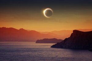 solar-eclipse-over-a-yellow-orange-sky-cliffs-and-the-sea-m.jpg