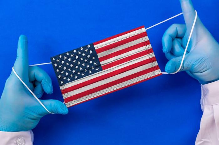 blue-gloved-hands-stretching-out-a-surgical-mask-printed-with-the-usa-flag-m.jpg