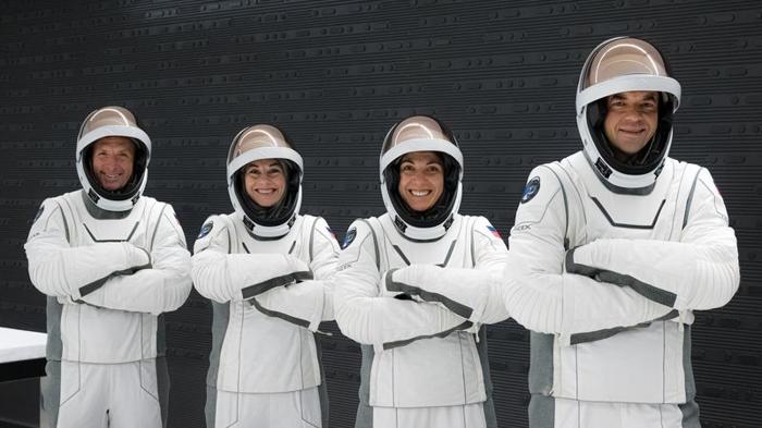 I quattro membri dell'equipaggio indossano le loro tute spaziali, si mettono in posa con le braccia incrociate e sorridono