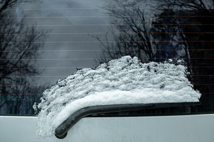 tergicristallo del lunotto di un'auto coperto da uno strato di neve scongelato dal vetro a seguito del riscaldamento con strisce riscaldanti, primo piano.