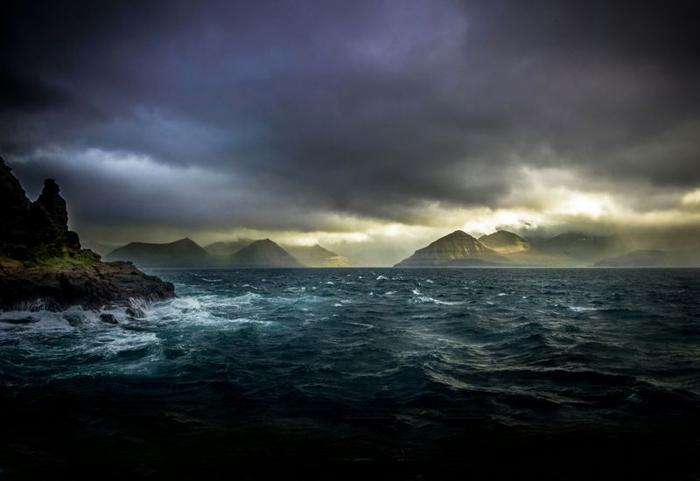 Scena cupa di onde che si infrangono su isole rocciose