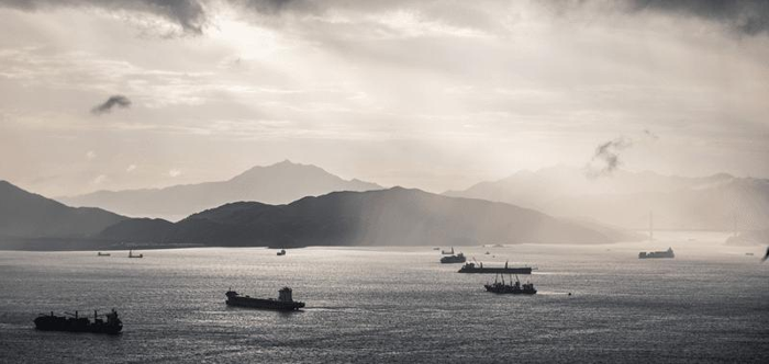 Le navi portacontainer navigano attraverso il tramonto argentato del Mar Cinese Meridionale. Credito immagine: Gorma Kuma/Shutterstock.com