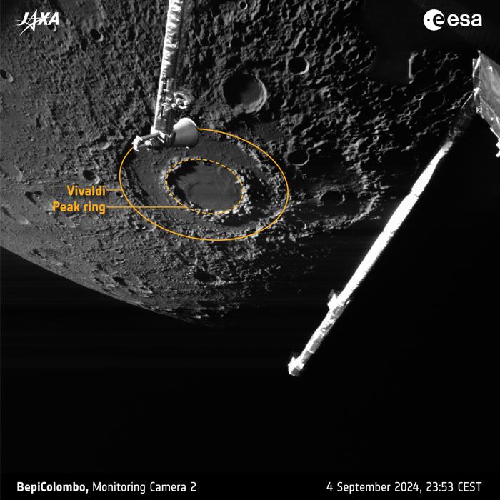 Pianeta Mercurio sullo sfondo con la sua superficie grigia, craterizzata e segnata da buchi. In primo piano ci sono alcune parti della navicella spaziale. Il focus principale è un cratere con un doppio bordo che assomiglia a un ciambellone piatto.