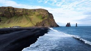 Vista aerea della spiaggia di sabbia nera di Reynisfjara e degli scogli marini in Islanda.