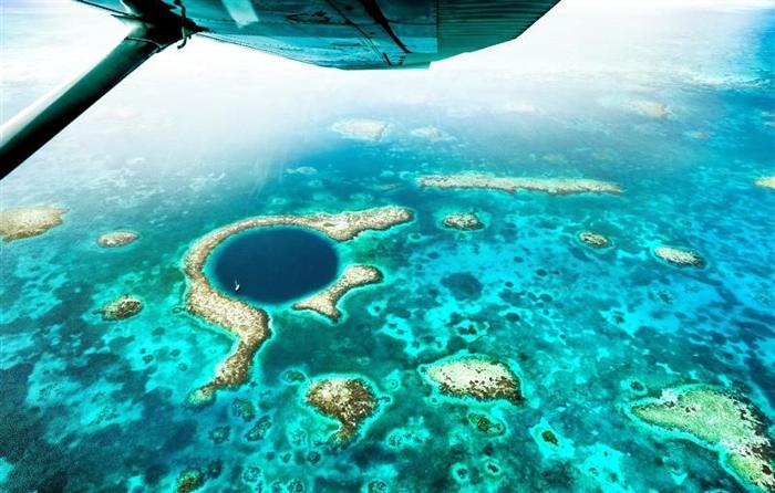 Vista aerea del Grande Buco Blu scattata da un aereo che vola sopra il Sistema di Riserva della Barriera Corallina del Belize