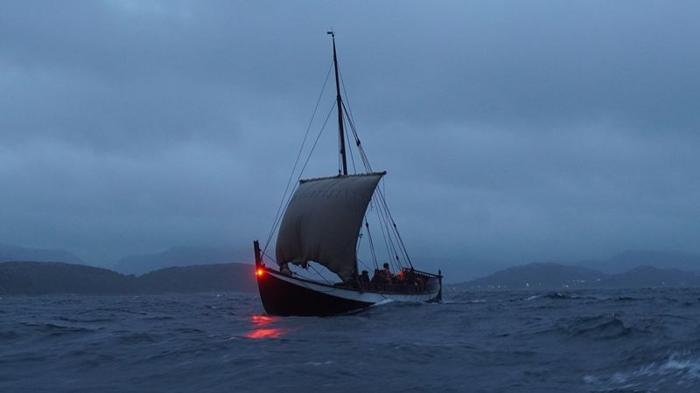 Una foto di una delle navi da spedizione norrene ricreate che naviga di notte.