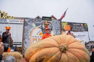 Uomo in piedi accanto al suo enorme zucca premiata