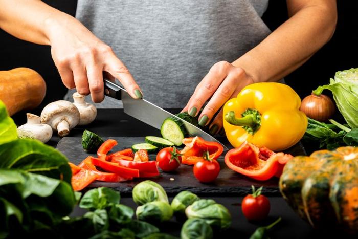 dettaglio delle mani di qualcuno che taglia le verdure con un coltello