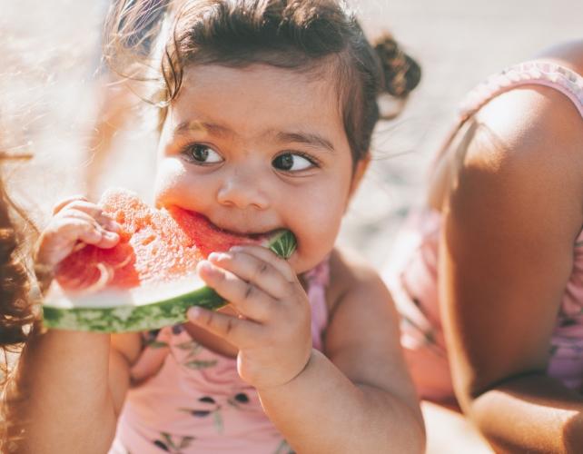 Un bambino che mangia una fetta di anguria