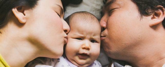 Due genitori baciano il loro bambino