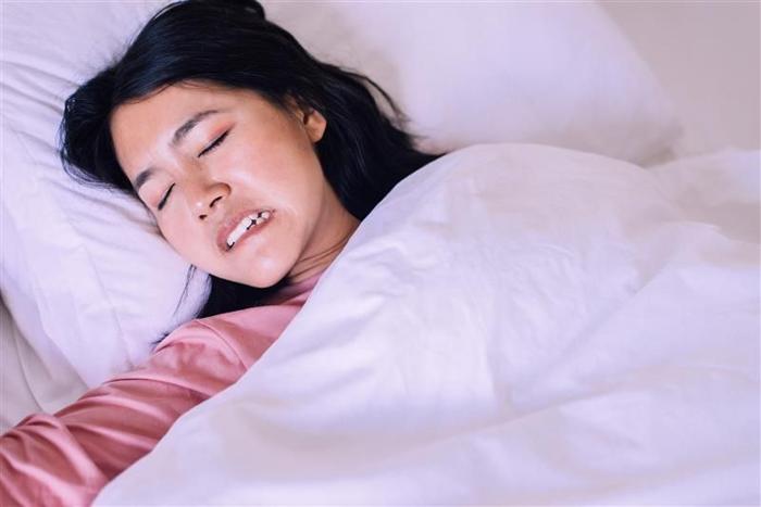 Donna con bruxismo che digrigna i denti nel sonno