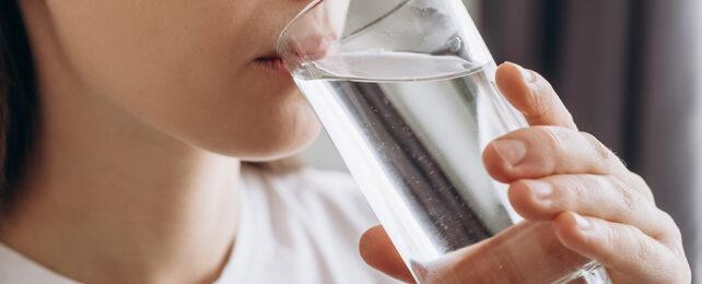 donna che beve acqua da un bicchiere