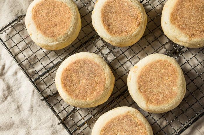 Scatto aereo di sei muffin inglesi disposti su una griglia per raffreddare su una tovaglia color crema