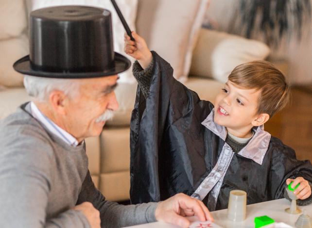 nonno con un cappello a cilindro mentre il nipote lo tocca con una bacchetta magica