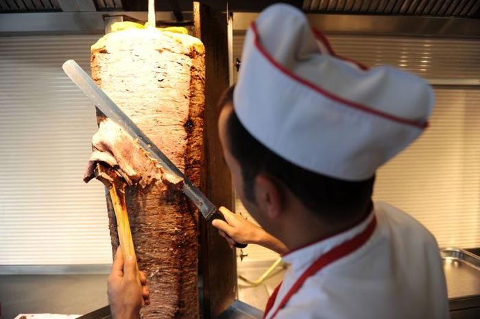 Uno chef in un ristorante turco affetta la carne da un girarrosto per kebab.