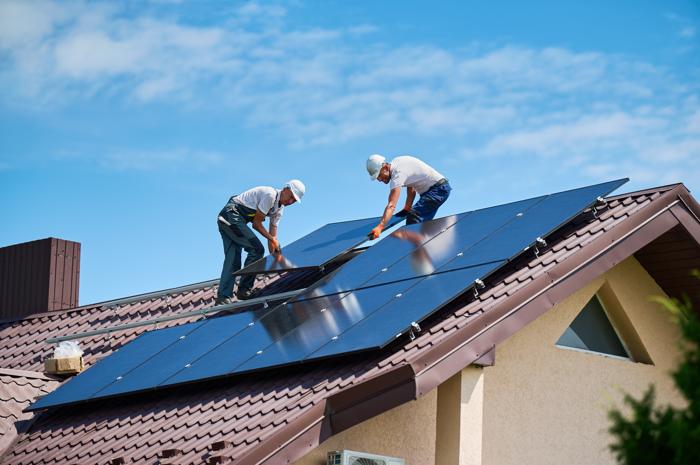 Due lavoratori che installano un impianto di pannelli solari sul tetto di una casa