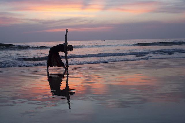 silhouette di una persona che fa yoga sulla spiaggia al tramonto