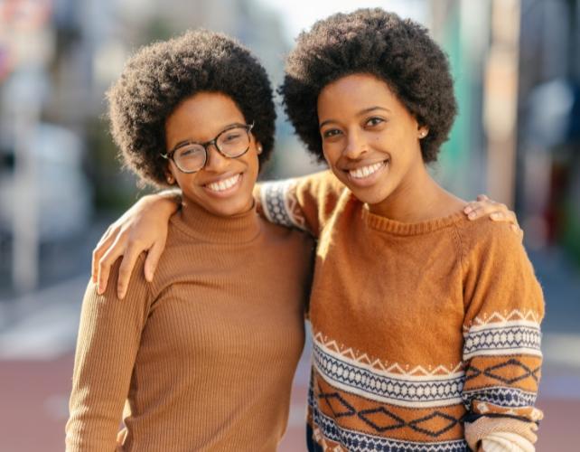 Sorelle gemelle sorridenti con le braccia intorno l'una all'altra