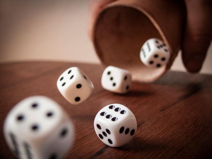 five-dice-being-thrown-out-of-a-cup-onto-a-table-m.jpg