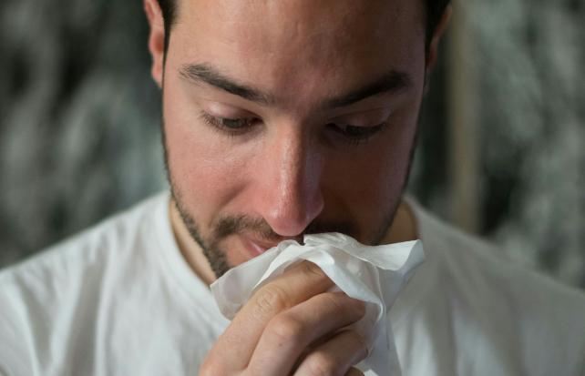 uomo che si soffia il naso