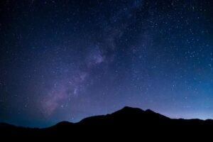 Una foto che mostra la Via Lattea nel cielo notturno sopra una silhouette di montagna.