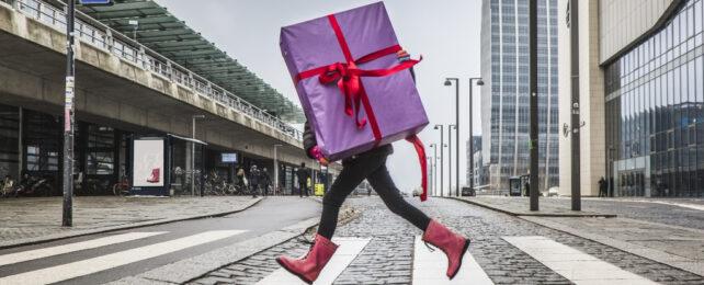 persona che trasporta un grande regalo attraverso la strada