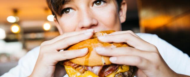 adolescente che mangia un hamburger