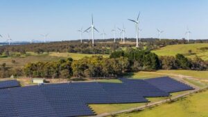 Vista aerea di un parco eolico e solare ibrido che mostra le grandi turbine eoliche sullo sfondo per la fornitura di energia pulita rinnovabile situato a Bannister, NSW, Australia